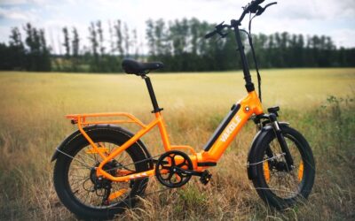 Vakole VT4 Elektro-Klapprad in Seitenansicht mit breiten 20-Zoll-Fatbike-Reifen, orangem Rahmen und aufrechter Sitzposition auf einem Feldweg im Test